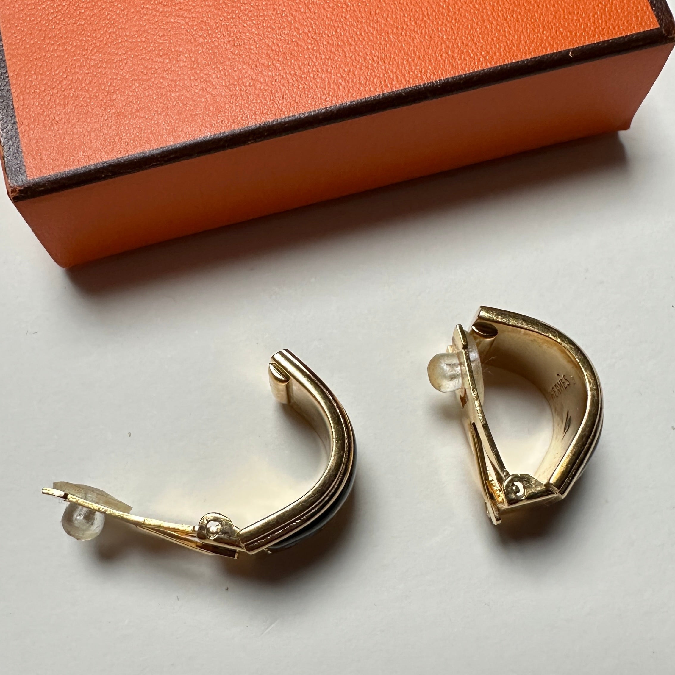 Design latéral bombé des boucles d'oreilles Hermès vintage, alliant émail coloré et bordure or.