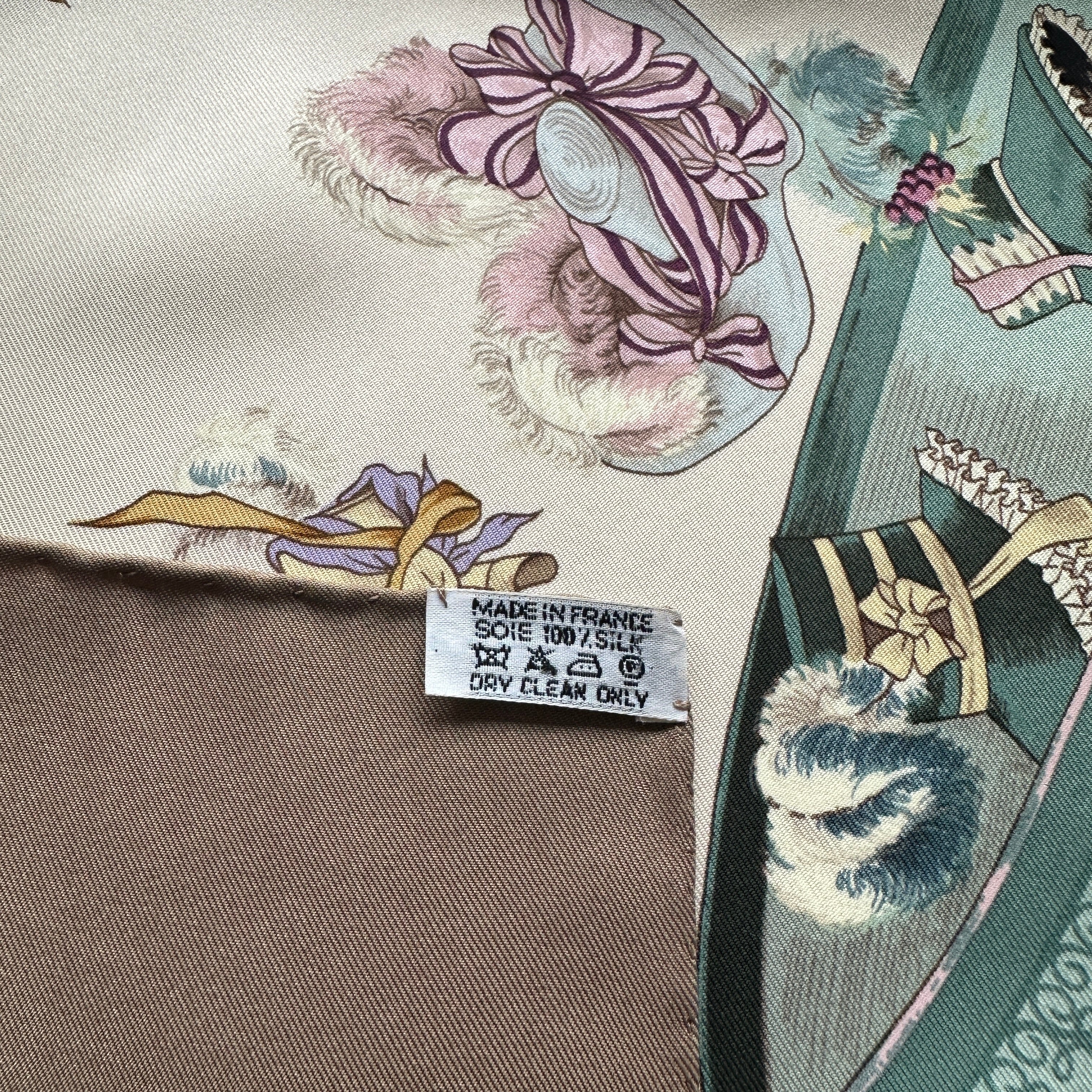 Étiquette de composition vintage "Made in France - Soie 100% Silk - Dry Clean Only" cousue sur le bord roulotté marron.