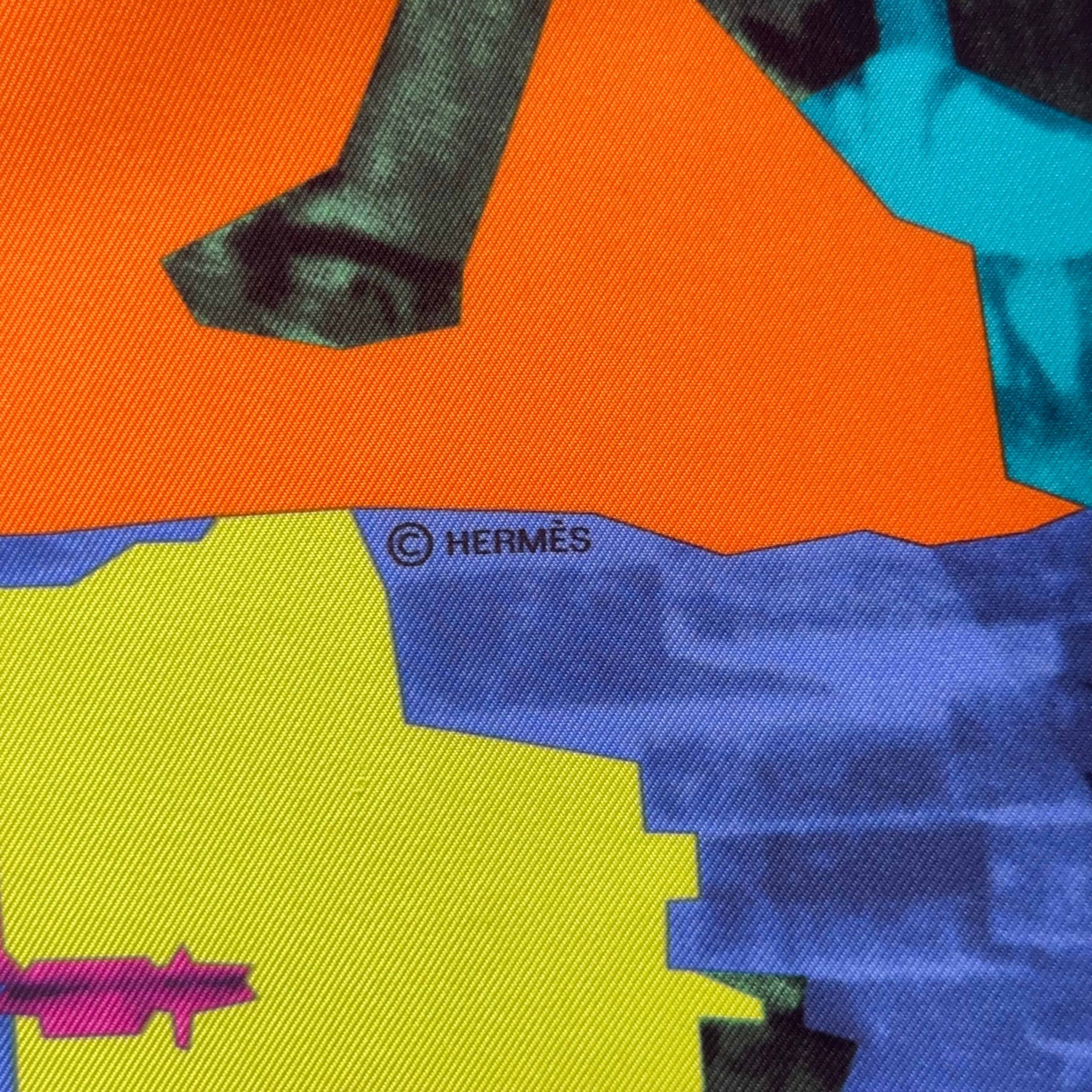 Mention du copyright "© HERMÈS" imprimée en noir à la jonction des blocs de couleurs orange et bleu.