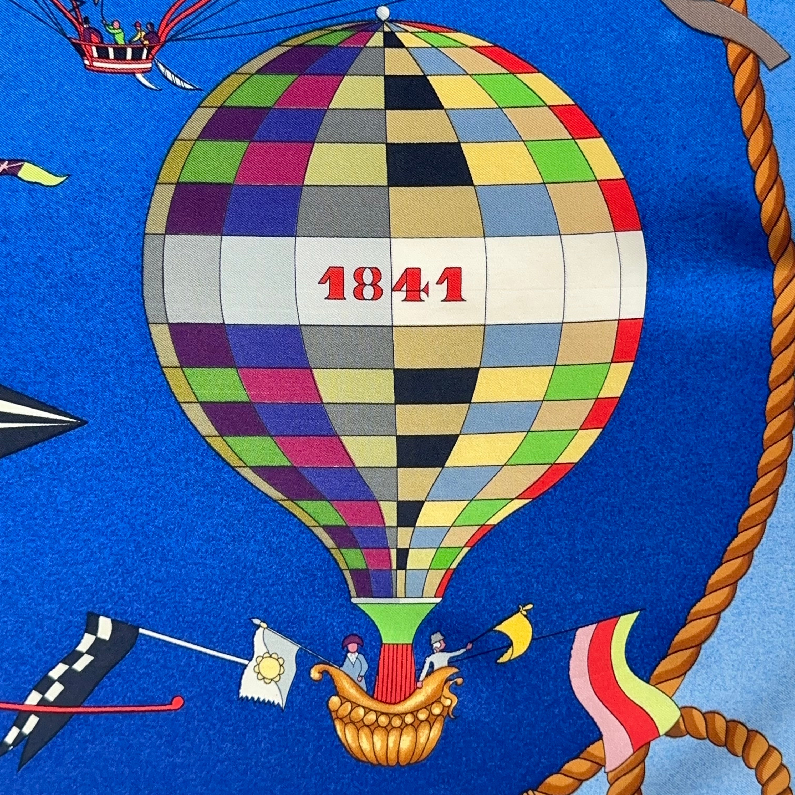 Détail d'une grande montgolfière centrale à motif damier multicolore datée "1841" avec nacelle dorée.